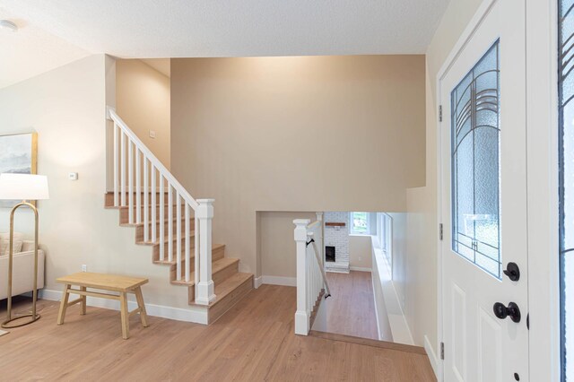 8464 Greenwood Dr, Mounds View, MN 55112 - foyer entrance featuring wood finished floors, stairs, baseboards, lofted ceiling, and a brick fireplace