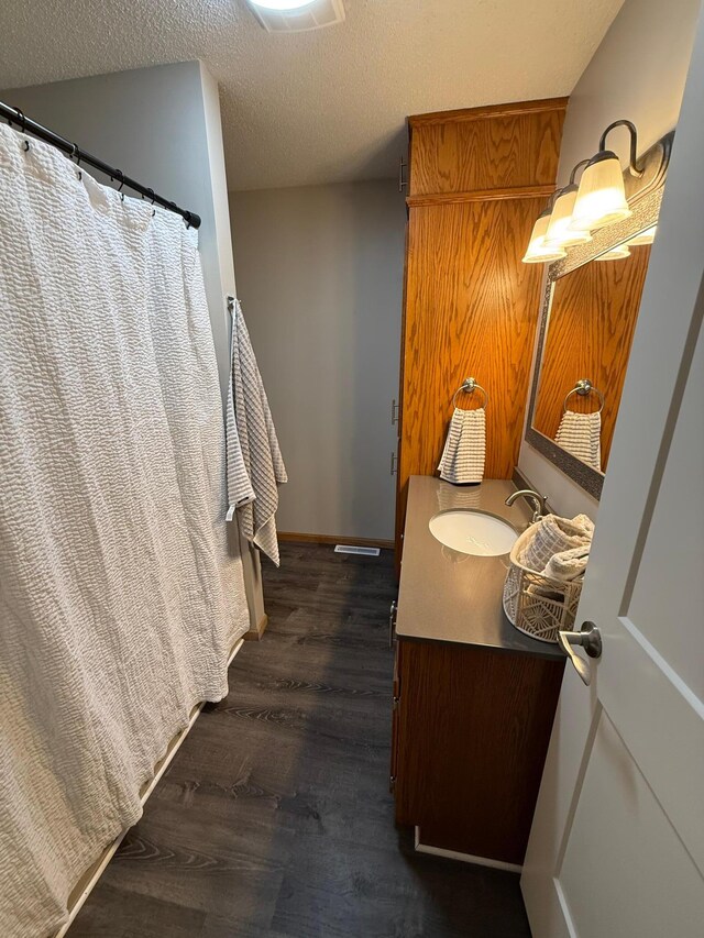50429 245th Ave, Staples Twp, MN 56479 - full bathroom featuring wood finished floors, vanity, a textured ceiling, a shower with shower curtain, and baseboards