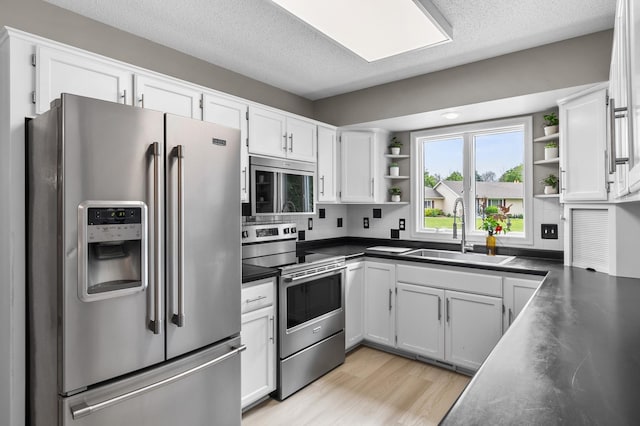 216 Crestview Cir, Jordan, MN 55352 - kitchen featuring appliances with stainless steel finishes, a sink, open shelves, dark countertops, and white cabinetry