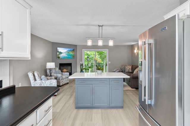 216 Crestview Cir, Jordan, MN 55352 - kitchen with high end fridge, a warm lit fireplace, open floor plan, light wood-type flooring, and white cabinetry