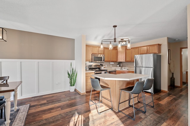 12828 43rd St NE, Saint Michael, MN 55376 - kitchen with stainless steel appliances, light countertops, dark wood-style floors, a breakfast bar area, and decorative backsplash