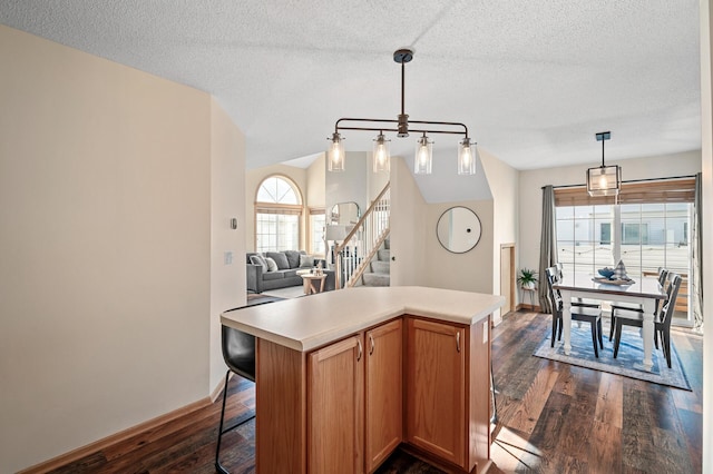 12828 43rd St NE, Saint Michael, MN 55376 - kitchen featuring dark wood finished floors, light countertops, a breakfast bar, a kitchen island, and decorative light fixtures