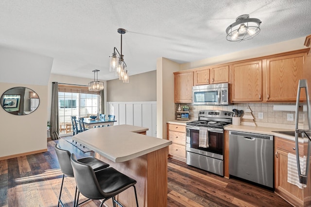 12828 43rd St NE, Saint Michael, MN 55376 - kitchen featuring stainless steel appliances, a center island, a kitchen bar, light countertops, and tasteful backsplash