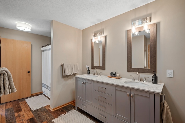 12828 43rd St NE, Saint Michael, MN 55376 - bathroom with double vanity, wood finished floors, baseboards, a textured ceiling, and a shower with curtain