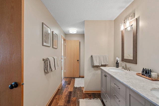 12828 43rd St NE, Saint Michael, MN 55376 - bathroom featuring wood finished floors, double vanity, baseboards, and a textured ceiling