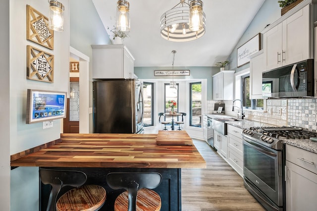15657 Fish Point Rd SE, Prior Lake, MN 55372 - kitchen featuring appliances with stainless steel finishes, a sink, tasteful backsplash, vaulted ceiling, and light wood-style floors