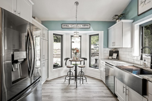 15657 Fish Point Rd SE, Prior Lake, MN 55372 - kitchen with appliances with stainless steel finishes, a sink, decorative backsplash, light wood-style floors, and light stone counters