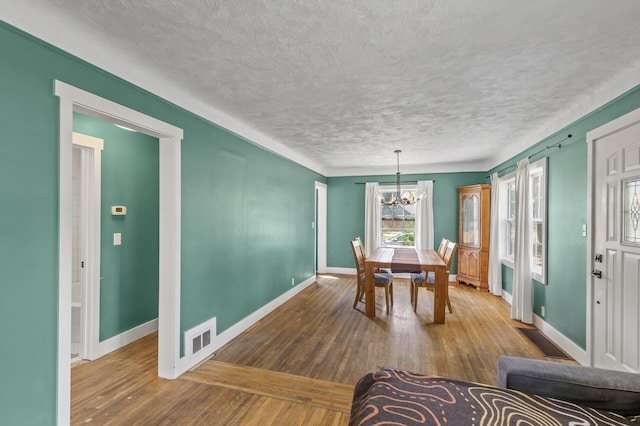7537 Wentworth Ave, Richfield, MN 55423 - dining area with a chandelier, a textured ceiling, baseboards, and wood-type flooring