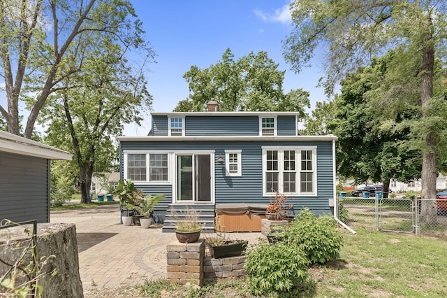 7537 Wentworth Ave, Richfield, MN 55423 - rear view of house with a hot tub, a patio, a chimney, and a gate