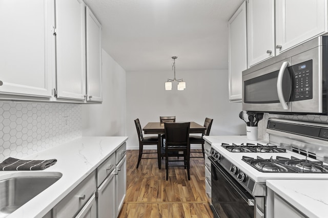 4207 Lakeside Ave N Unit 328, Brooklyn Center, MN 55429 - kitchen with gas range gas stove, stainless steel microwave, tasteful backsplash, a chandelier, and light wood-style floors