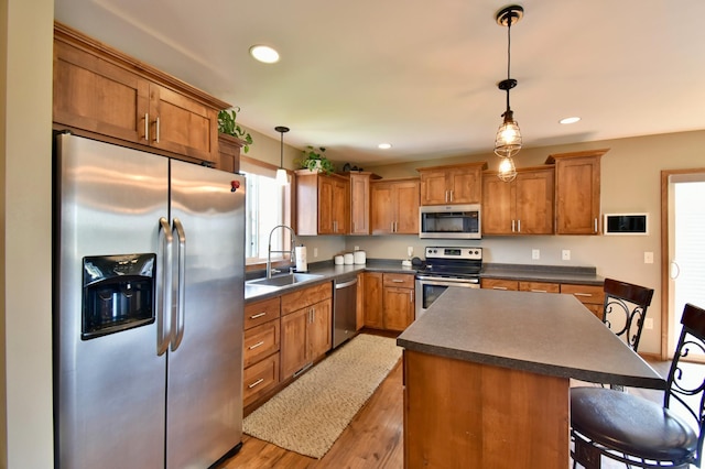 1756 34th St NE, Sauk Rapids, MN 56379 - kitchen with appliances with stainless steel finishes, a sink, dark countertops, brown cabinetry, and light wood-style floors