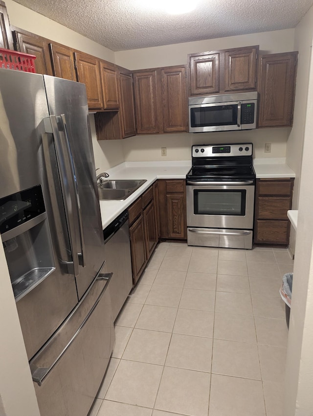 10451 Greenbrier Rd Unit 115, Minnetonka, MN 55305 - kitchen with stainless steel appliances, a sink, light countertops, a textured ceiling, and light tile patterned floors