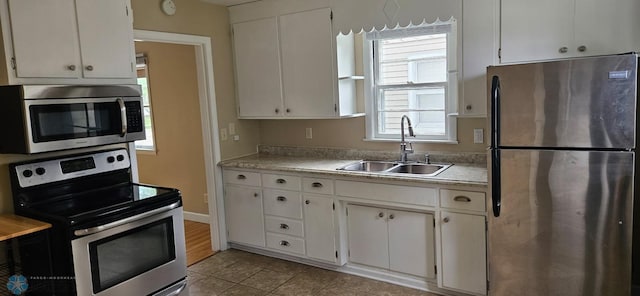 911 16th St N, Moorhead, MN 56560 - kitchen with appliances with stainless steel finishes, a sink, white cabinetry, light countertops, and light tile patterned floors