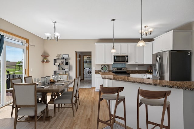 1498 Fox Meadow Dr, Delano, MN 55328 - kitchen featuring appliances with stainless steel finishes, washer and dryer, a chandelier, light wood finished floors, and white cabinetry