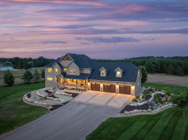 view of front of house featuring driveway, stone siding, a front yard, a porch, and an attached garage