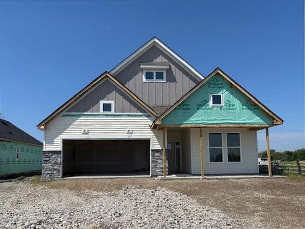 7665 Swan St, Lino Lakes, MN 55038 - view of front of property with board and batten siding, stone siding, dirt driveway, and an attached garage