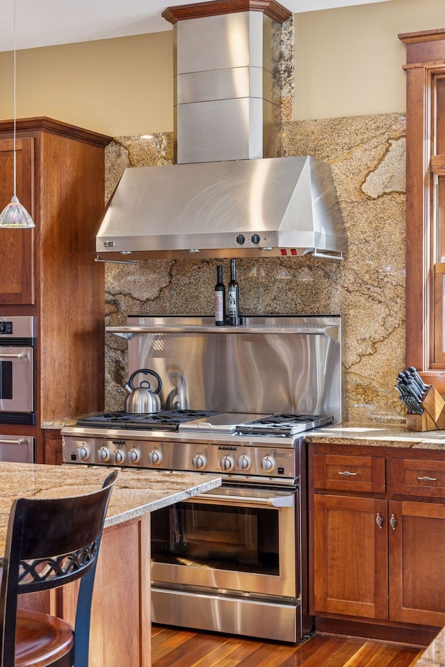 12159 Quail Avenue Ln N, Stillwater, MN 55082 - kitchen featuring stainless steel appliances, wall chimney exhaust hood, wood finished floors, brown cabinets, and a warming drawer