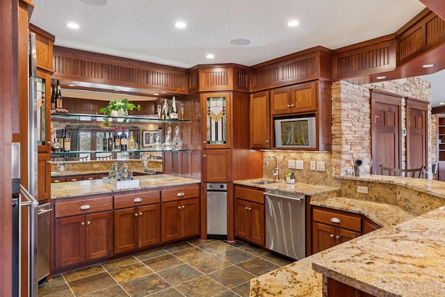12159 Quail Avenue Ln N, Stillwater, MN 55082 - kitchen with stainless steel dishwasher, a sink, light stone counters, tasteful backsplash, and brown cabinetry