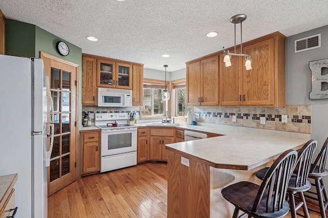 5392 Highland Trl, Big Lake, MN 55309 - kitchen featuring white appliances, a textured ceiling, a peninsula, light wood-style floors, and decorative backsplash