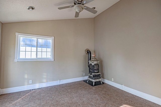 546 2nd St SE, Perham, MN 56573 - empty room with lofted ceiling, a wood stove, a ceiling fan, tile patterned floors, and baseboards