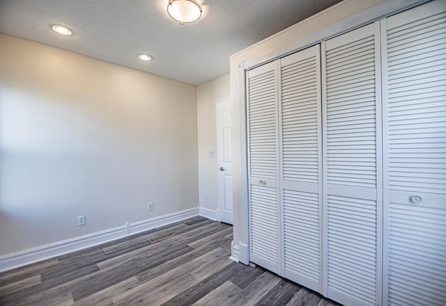 546 2nd St SE, Perham, MN 56573 - unfurnished bedroom with a closet, dark wood-style flooring, a textured ceiling, baseboards, and recessed lighting