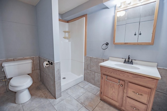 546 2nd St SE, Perham, MN 56573 - bathroom with tile walls, toilet, a wainscoted wall, vanity, and a walk in shower