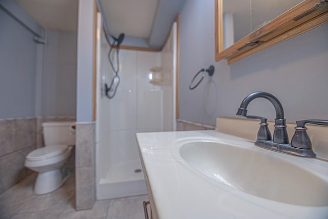 546 2nd St SE, Perham, MN 56573 - bathroom with a stall shower, a sink, toilet, wainscoting, and tile walls