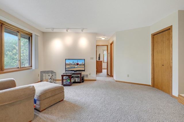 living room with light colored carpet, baseboards, and rail lighting