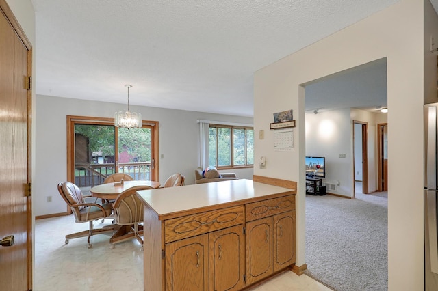 kitchen with a peninsula, light countertops, a chandelier, brown cabinetry, and baseboards