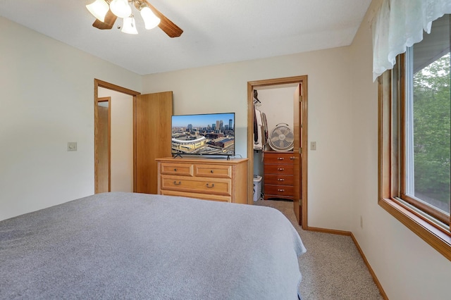 carpeted bedroom with a spacious closet, baseboards, ceiling fan, and a closet