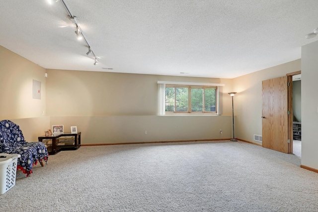 unfurnished room featuring carpet flooring, track lighting, a textured ceiling, and baseboards