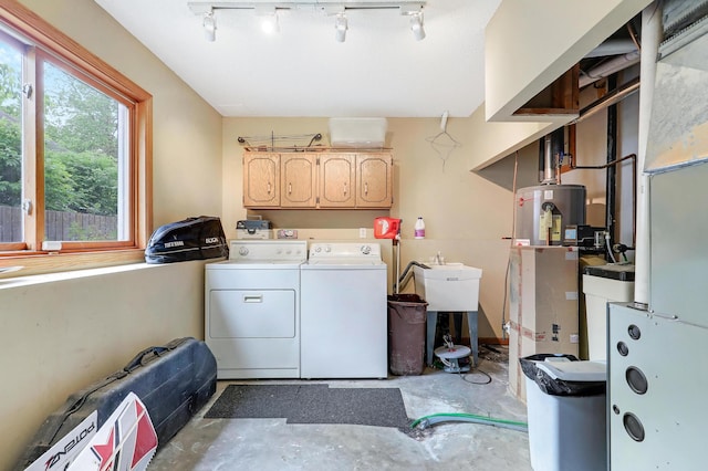 laundry area with independent washer and dryer, gas water heater, cabinet space, and track lighting