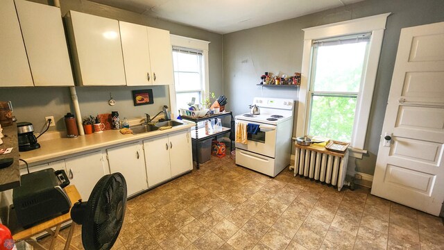 728 8th St N, Fargo, ND 58102 - kitchen with white range with electric stovetop, a sink, light countertops, radiator heating unit, and white cabinets