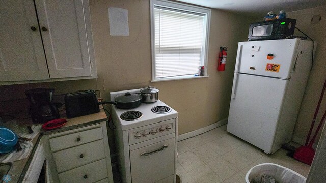 728 8th St N, Fargo, ND 58102 - kitchen with white appliances, white cabinetry, light countertops, and baseboards