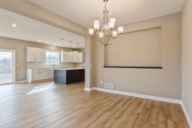14965 105th Pl N, Maple Grove, MN 55369 - kitchen with light countertops, white cabinets, backsplash, a chandelier, and light wood-style flooring