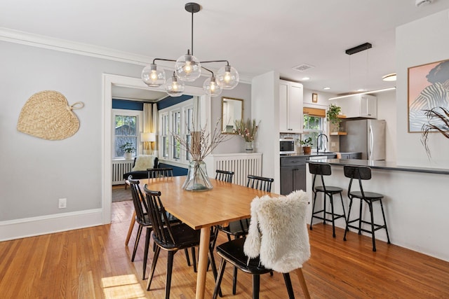 1310 Fairmount Ave, Saint Paul, MN 55105 - dining space with healthy amount of natural light, radiator, light wood-style flooring, baseboards, and crown molding