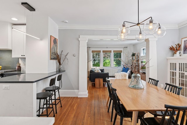 1310 Fairmount Ave, Saint Paul, MN 55105 - dining area with crown molding, light wood-type flooring, decorative columns, baseboards, and radiator