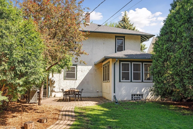 1310 Fairmount Ave, Saint Paul, MN 55105 - back of property with stucco siding, a chimney, a lawn, a patio, and roof with shingles