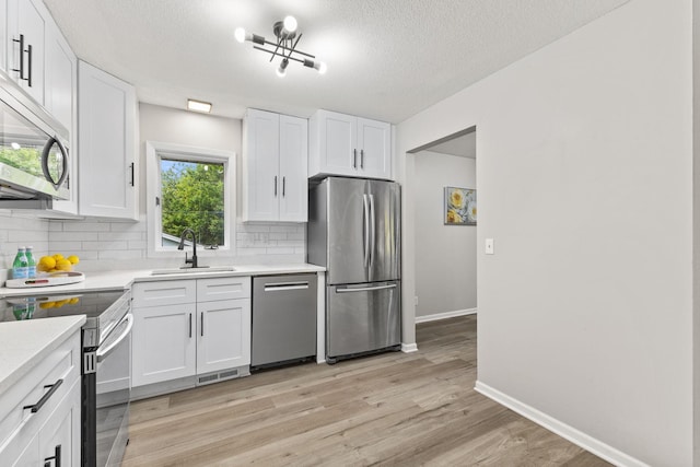 228 16th Ave SW, New Brighton, MN 55112 - kitchen with stainless steel appliances, a sink, decorative backsplash, white cabinets, and light countertops