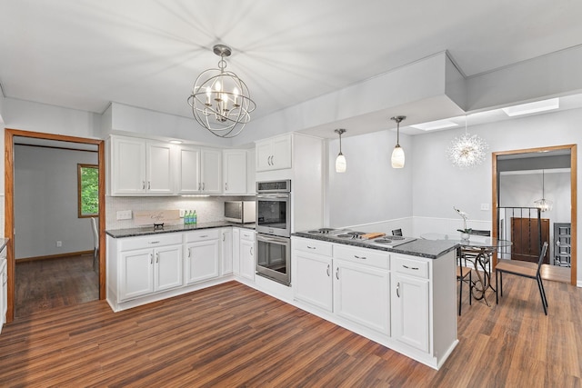 708 Brigadoon Cir, Shoreview, MN 55126 - kitchen featuring a peninsula, stainless steel appliances, a chandelier, dark wood finished floors, and white cabinetry
