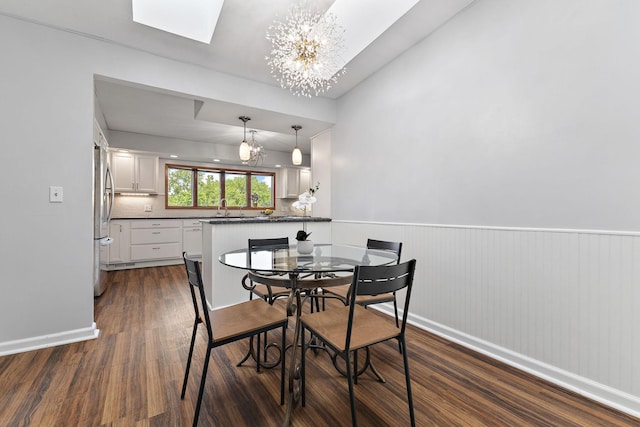 708 Brigadoon Cir, Shoreview, MN 55126 - dining room featuring a chandelier, dark wood-type flooring, a skylight, a wainscoted wall, and baseboards
