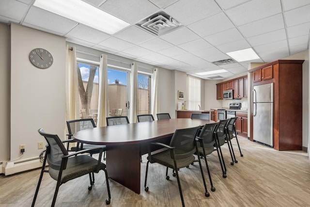 1425 28th St Unit 519, Minneapolis, MN 55408 - dining room featuring light wood finished floors, a drop ceiling, and a baseboard heating unit
