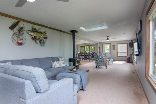 692 Round Lake Ln, Georgetown Twp, WI 54853 - carpeted living room featuring a wood stove, ceiling fan, a textured ceiling, and baseboards