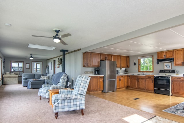 692 Round Lake Ln, Georgetown Twp, WI 54853 - kitchen with gas range, freestanding refrigerator, ceiling fan, under cabinet range hood, and light countertops