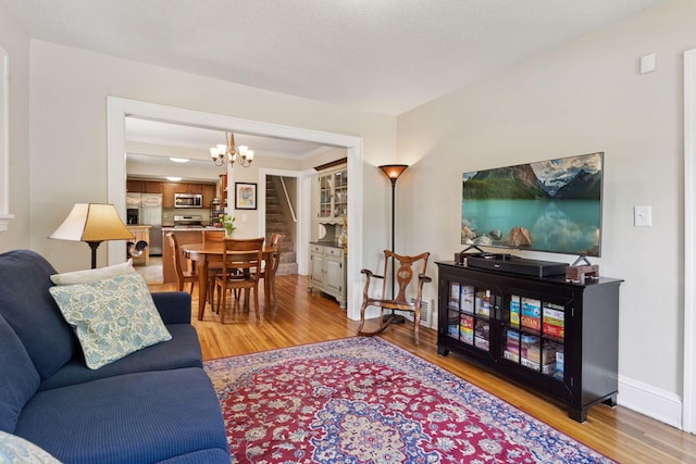 4034 Nokomis Ave, Minneapolis, MN 55406 - living room featuring stairway, light wood finished floors, a chandelier, and baseboards