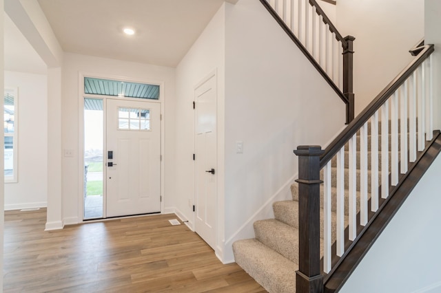 foyer featuring stairway, wood finished floors, healthy amount of natural light, and recessed lighting