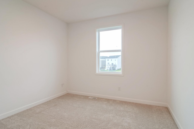 empty room featuring light colored carpet and baseboards