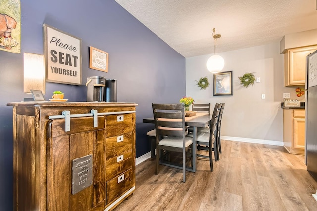 2727 43rd St Unit 102, Minneapolis, MN 55410 - dining room featuring light wood-style floors, lofted ceiling, baseboards, and a textured ceiling