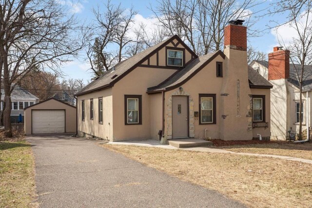 1750 Sims Ave, Saint Paul, MN 55106 - english style home with a shingled roof, a chimney, asphalt driveway, an outdoor structure, and a garage