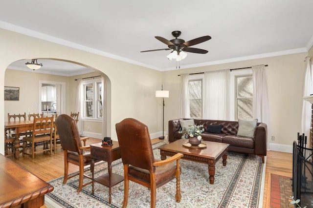1750 Sims Ave, Saint Paul, MN 55106 - living room with arched walkways, light wood finished floors, ceiling fan, baseboards, and crown molding